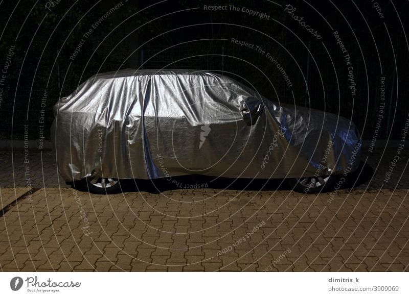 Auto mit Schutzhülle bei Nacht PKW Silber schützend Deckung Wetter Gewebe reflektierend Fahrzeug Automobil wasserbeständig wasserdicht bedeckt geparkt Straße