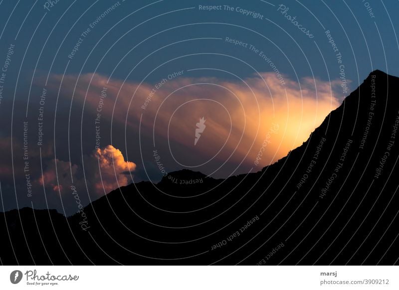 Von der untergehenden Sonne beleuchtete Wolken, die hinter einem Berg hervordrängen Sonnenuntergang stimmungsvoll Wolken Stimmung Berge u. Gebirge Natur