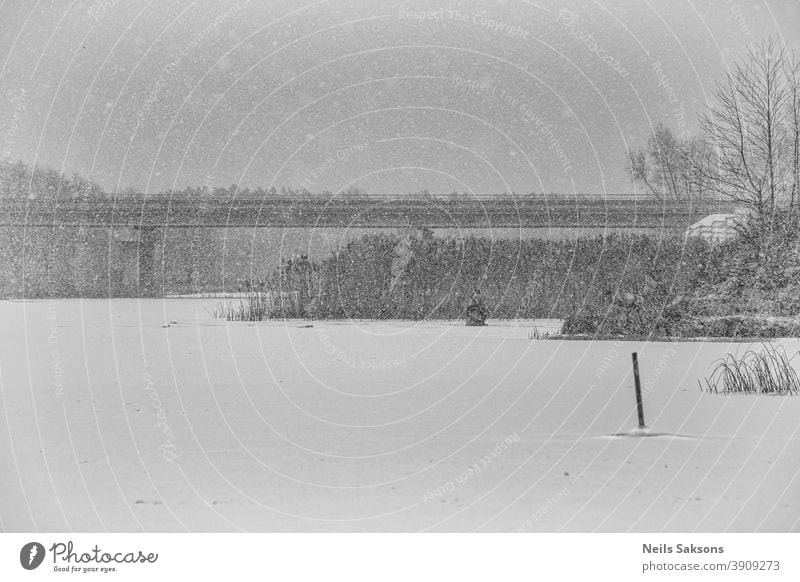 einsamer Eisfischer auf dem Fluss im Schneesturm Einsamkeit Fischen Eisangeln Hobby Wasser Winter Schneefall Schneelandschaft Schneeflocke Schneeglöckchen