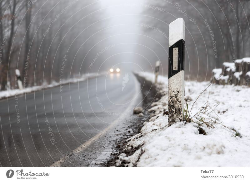 ein Auto, das auf einer nebligen Winterwaldstraße fährt Nebel Auto auf nebliger Straße Auto auf winterlicher Straße PKW Abend Fahrzeugbeleuchtung Auto in Gefahr