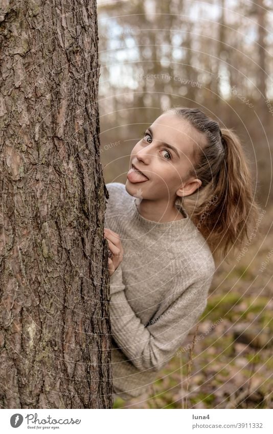 fröhliches Mädchen steckt Zunge raus rausstrecken frech Jugendliche übermütig lachen rebellisch Grimasse Baum Mimik Pferdeschwanz provokant entspannt teenager