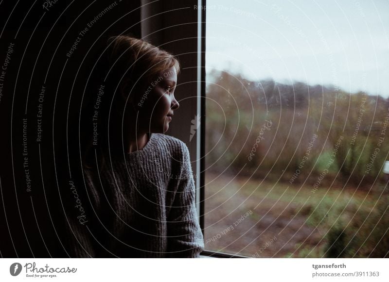 Kind schaut nachdenklich aus dem Fenster Mädchen Kindheit Blick Mensch Farbfoto Innenaufnahme Porträt 1 Herbst nachdenkend beobachten beobachtend blond