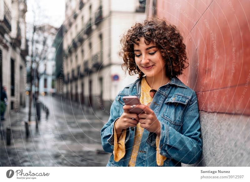 Junge Frau mit Telefon krause Haare jung Straße Kaukasier per Telefon Funktelefon Smartphone benutzend Mitteilung Technik & Technologie Typ Tippen Texten