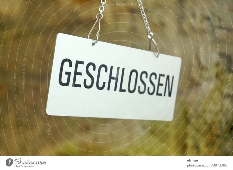 Hinter einer Glasscheibe hängt ein Schild "GESCHLOSSEN"  / lockdown / Coronakrise geschlossen hängen Glastür Tür Hinweisschild Laden Geschäft Prävention