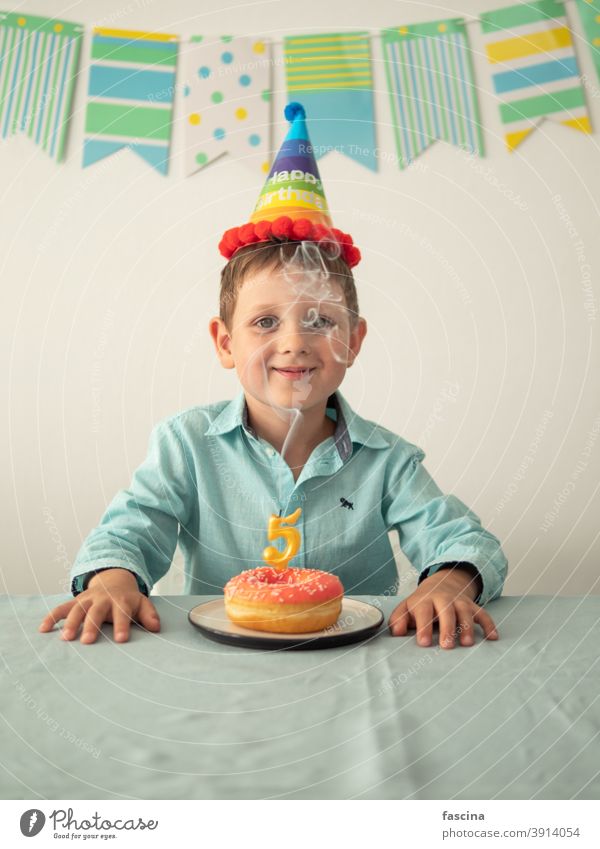 Kind durch Rauch von Kerze auf festlichen Donut Geburtstag Krapfen Junge Hände fünf Jahr sein wenig Lächeln Halt Teller Doughnut in die Kamera schauen Spaß