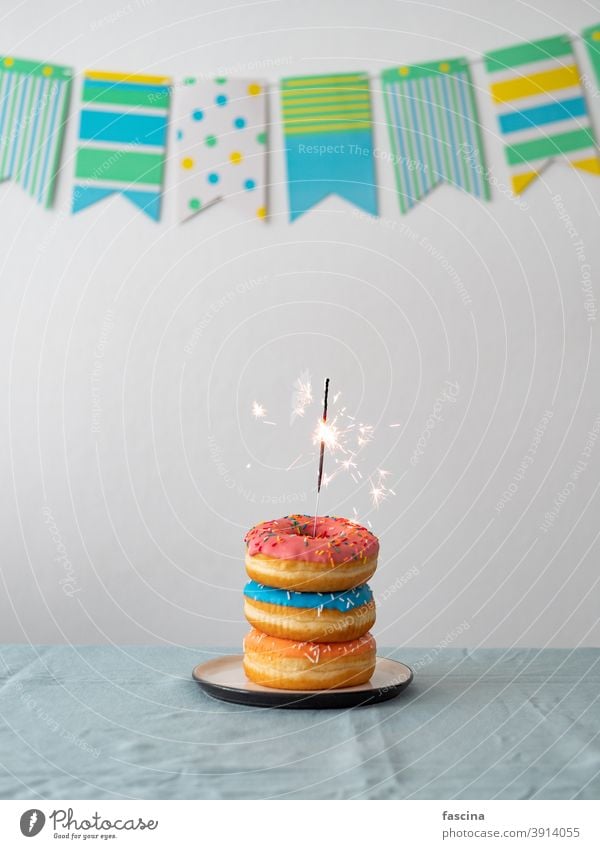 Geburtstag Donuts Kuchen mit Wunderkerze auf dem Tisch Donuts-Kuchen Bengallicht Girlande Geburtstags-Donuts Stapel süß Bengalen Licht lecker Doughnuts Party