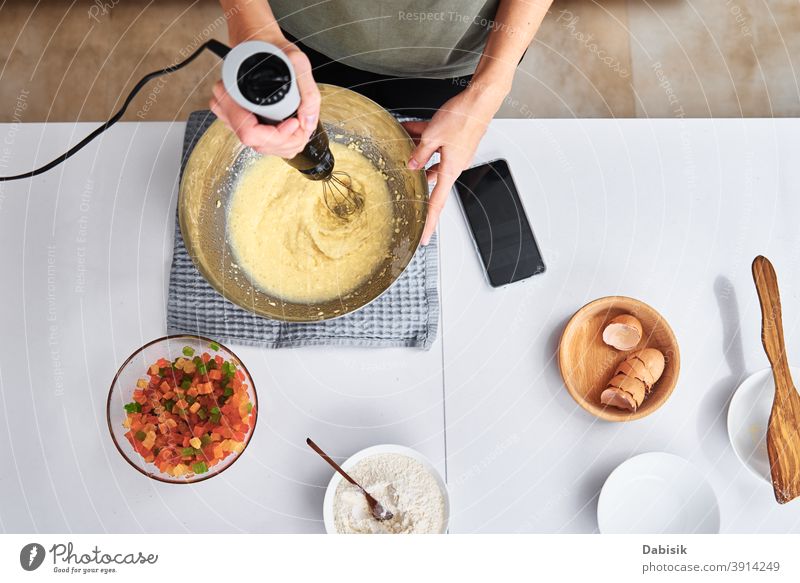 Frau in der Küche beim Backen eines Kuchens. Hände schlagen den Teig mit einem elektrischen Mixer, Ansicht von oben Essen zubereiten Koch Rezept Zutaten