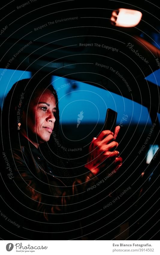 hispanische Frau mit Mobiltelefon im Auto bei Nacht. Reisen und Technologie Konzept Handy PKW Bildschirm reisen schön mittlerer Erwachsener Lebensstile klug