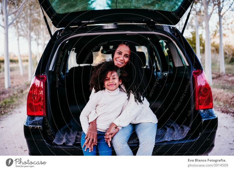 hispanische Mutter und Afrokindermädchen sitzen in einem Auto in der Natur. Herbstsaison. Familien- und Reisekonzept Porträt Tochter im Freien gemischte Rasse