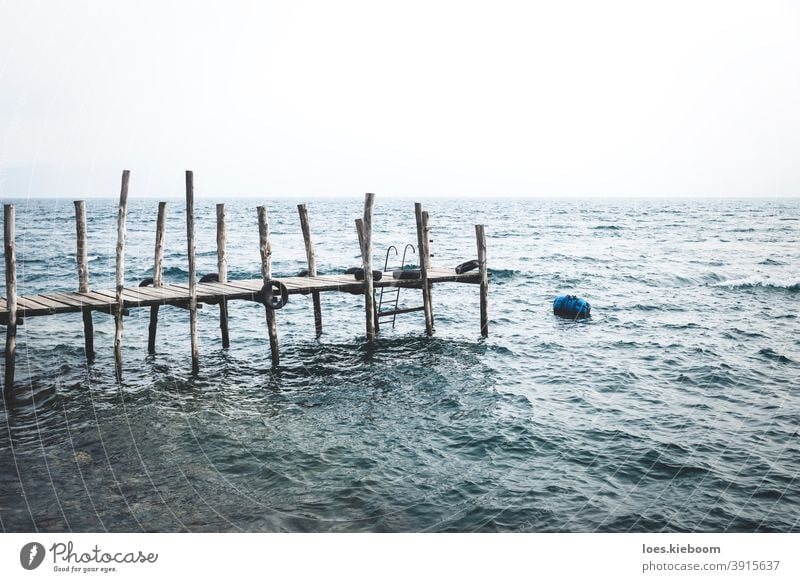 Dock mit stürmischen Wellen am See Atitlan an der Küste von Jailbalito, Guatemala Schiffswerft jailbalito Wasser Pier Vulkan Wolken Abenddämmerung