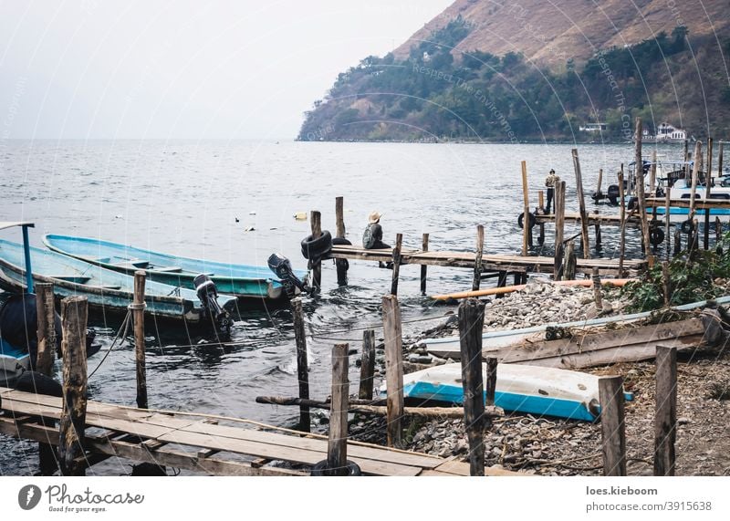 Einheimischer Mann mit Cowboyhut sitzt am Steg entlang des Atitlan-Sees an der Küste von Santa Cruz la Laguna, Guatemala Dock Schiffswerft santa cruz la laguna