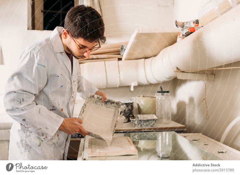 Handwerker bei der Arbeit mit Gips im Kunstatelier Kunstgewerbler verputzen Werkstatt Kunsthandwerker Form eingießen liquide Handarbeit Fähigkeit Mann männlich