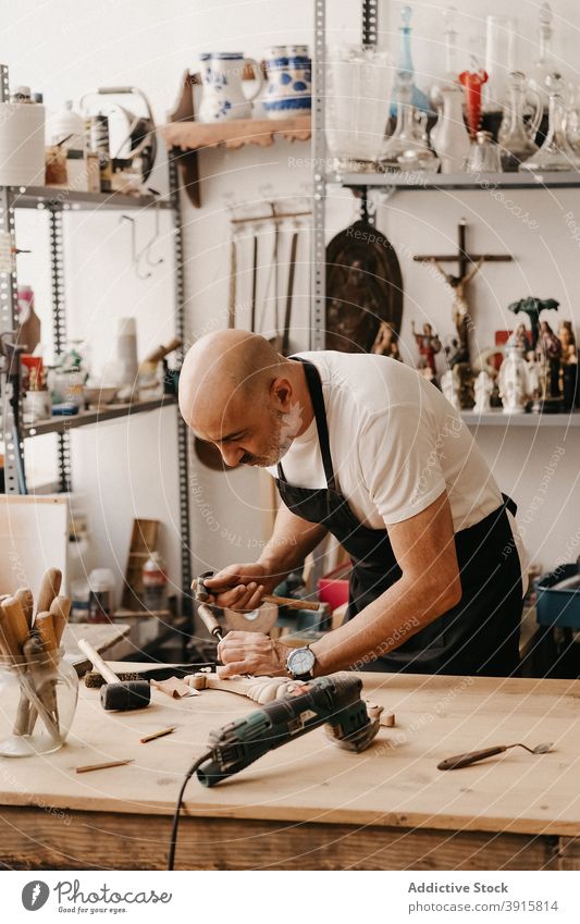 Kunsthandwerker bei der Herstellung von Holzdetails in der Werkstatt Zimmerer Holzarbeiten Beitel Hammer Arbeit kreieren schnitzen Instrument professionell