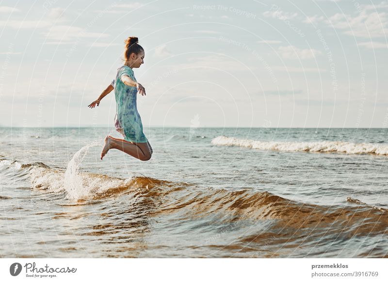 Mädchen, das es genießt, im Sommerurlaub über Wellen zu springen und seine Freizeit am Strand über dem Meer zu verbringen aufgeregt frei genießen positiv