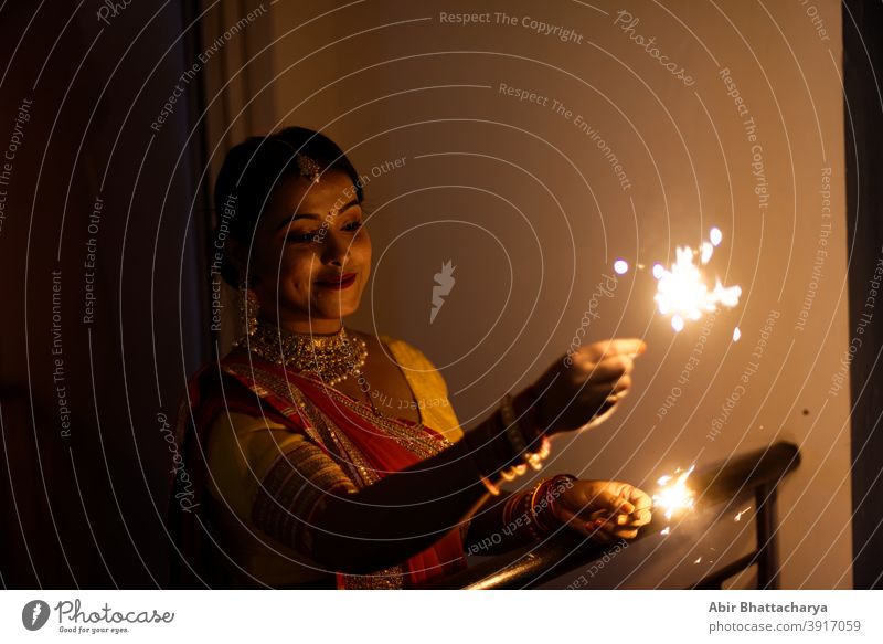 Junge und schöne indische Bengali Frau in indischen traditionellen Kleid feiert Diwali mit Feuer Cracker auf einem Balkon in der Dunkelheit. Indischer Lebensstil und Diwali-Feier