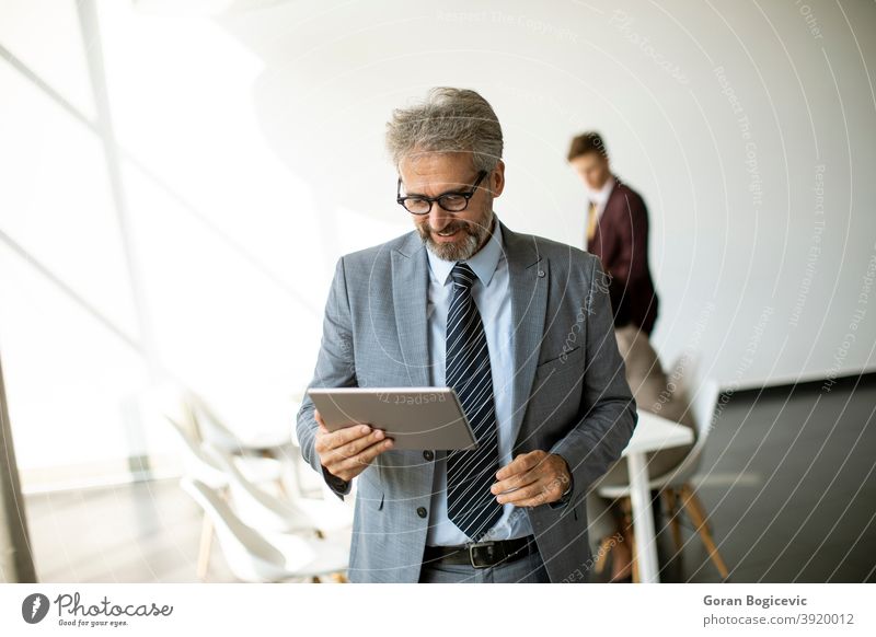 Gut aussehend reifen Geschäftsmann mit seinem Tablet im Büro Erwachsener Lebensalter allein attraktiv Business Geschäftsleute Karriere Kaukasier selbstbewusst