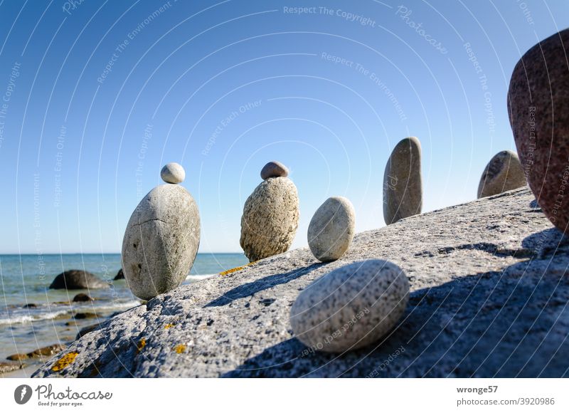 Steinmandl stehen auf einem großen Stein und blicken auf‘s Meer Steinmännl Steinmänner See Ostsee in Reihe stehen Strand Wasser Natur Küste