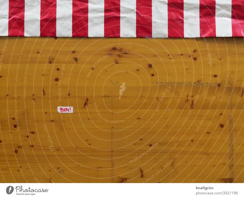 Rückseite eines Marktstandes mit gestreifter Plane und kleinem Aufkleber rot-weiß Holz Bretter Marktbude Astlöcher Farbfoto braun Streifen Außenaufnahme