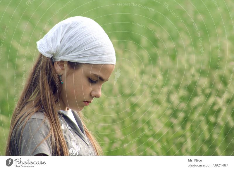 Junges Mädchen mit Kopfbedeckung blickt zu Boden Haare & Frisuren Oberkörper Mode Natur Kopftuch Gesicht Jugendliche Landschaft Wiese Lifestyle langhaarig Gras