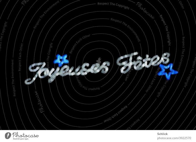 Text Joyeuses Fetes und blaue Sterne unscharf mit Bokeh Weihnachtsbeleuchtung text Joyeuses fetes Unschärfe silber Licht schwarzer hintergrund blendenflecken