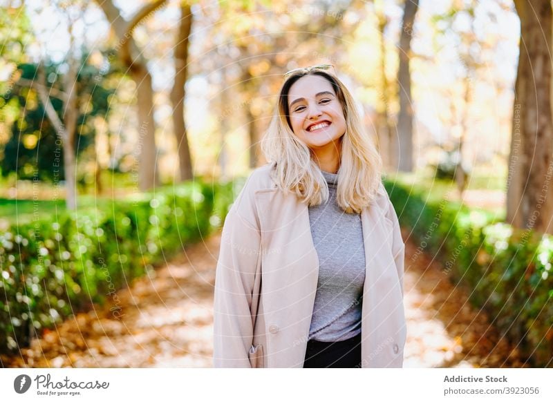 Junge Frau im Mantel im Herbst Park Outfit Lächeln schlendern Wochenende lässig jung heiter Glück Optimist Freude trendy angenehm froh positiv Dame stehen