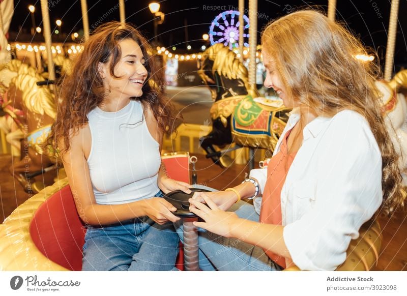 Fröhliche Freundinnen fahren Karussell auf Kirmes Jahrmarkt Spaß haben Mitfahrgelegenheit Glück heiter Lachen Zusammensein genießen jung Frau Sommer Abend