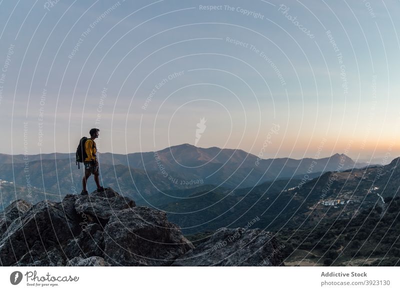 Reisender Mann steht auf felsigen Gipfel bei Sonnenuntergang Berge u. Gebirge Felsen Freiheit einsam Entdecker rau Abenteuer Rucksack Top Natur männlich Fernweh