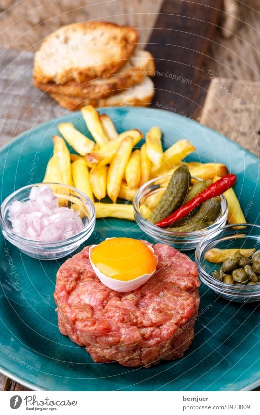 Steak Tartar mit offenem Ei auf Holz Tartare Eigelb HackSteak Hackfleisch Chili Peperoni Rindfleisch frisch Fleisch Essen gehackt rot Gewürz Gourmet Pfeffer