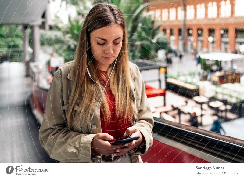 Junges Mädchen mit Kopfhörer Porträt jung 20s Vorderansicht blond hübsch Telefon per Telefon Funktelefon Kaukasier Blick Stehen Frau Smartphone hören benutzend