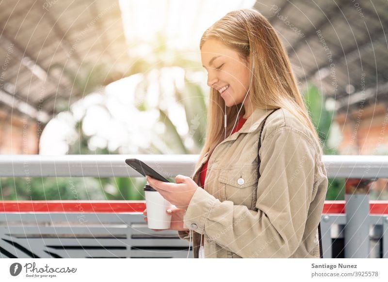 Smiley Mädchen Blick auf Telefon Seitenansicht Blick auf das Telefon Tasse Kaffee Kopfhörer Porträt jung 20s blond hübsch per Telefon Funktelefon Kaukasier