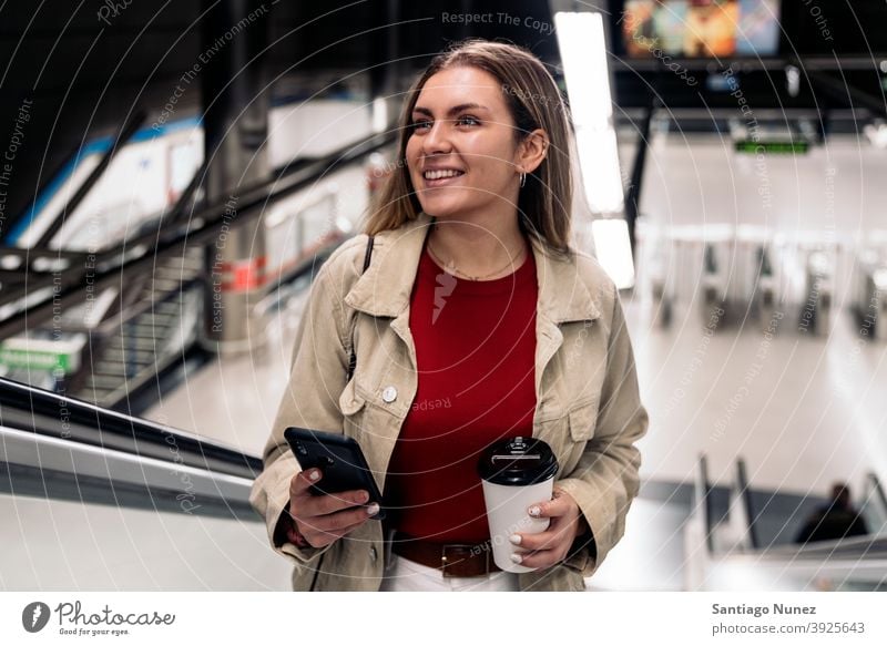 Glückliches Mädchen auf Rolltreppe Treppe Rolltreppen Station Bahnhof Frau jung Tasse Kaffee Telefon per Telefon Lächeln Vorderansicht Porträt 20s blond hübsch