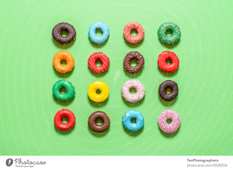 Schokoladen-Donuts in der Draufsicht. Mehrfarbig glasierte Krapfen obere Ansicht ausgerichtet sortiert Hintergrund gebacken Bäckerei blau Frühstück Kuchen