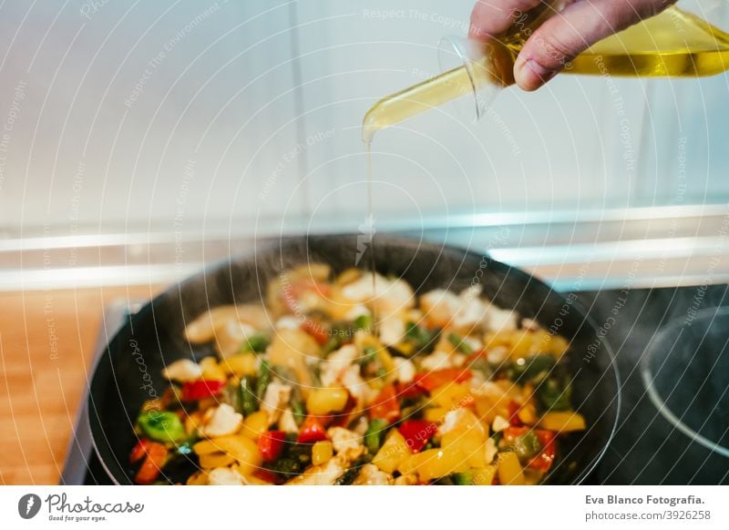 unkenntlich Mann bereitet Gemüse Essen in der Pfanne. Hinzufügen von Olivenöl. Gesundes Essen oliv Erdöl Lebensmittel Küche Paprika farbenfroh Gesundheit Möhre