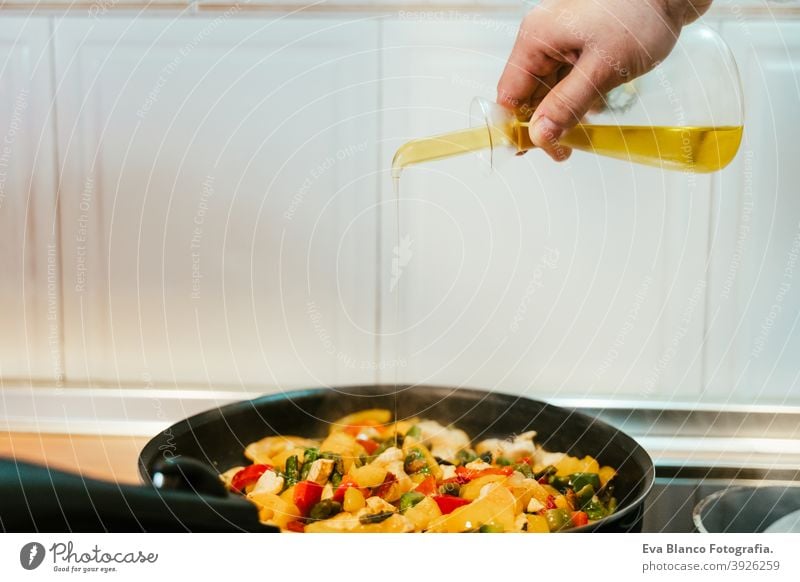 unkenntlich Mann bereitet Gemüse Essen in der Pfanne. Hinzufügen von Olivenöl. Gesundes Essen oliv Erdöl Lebensmittel Küche Paprika farbenfroh Gesundheit Möhre