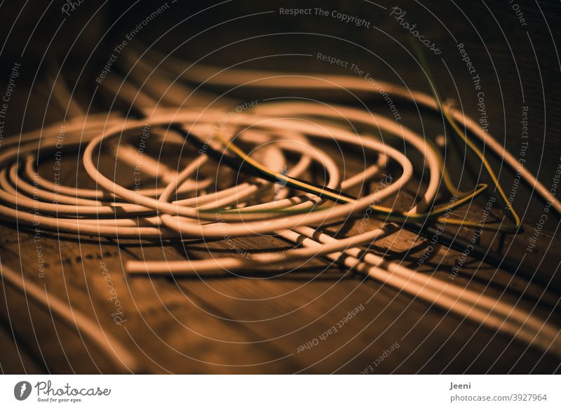 Auf dem Holzfußboden liegt ein Durcheinander von Kabeln Kabelsalat Stromkabel Technik & Technologie Elektrizität durcheinander Energie Verbindung Energiekrise