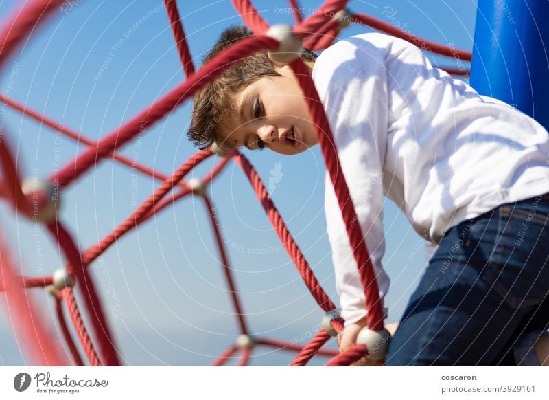 Lustiger Junge beim Klettern auf einem Spielplatz aktiv Aktivität Abenteuer Gleichgewicht Blauer Himmel Mut Kaukasier Kind Kindheit Kinder Klettergerüst Farbe