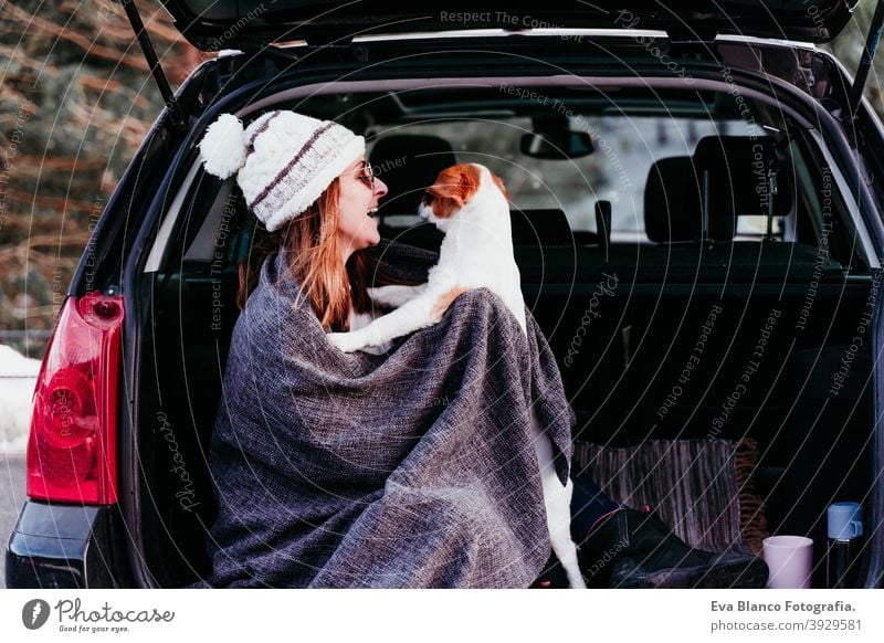 Junge Frau und niedlichen Jack Russel Hund im Auto. Wintersaison, verschneiten Berg Hintergrund Decke Natur Zusammensein Saison Fernweh Schönheit aktiv