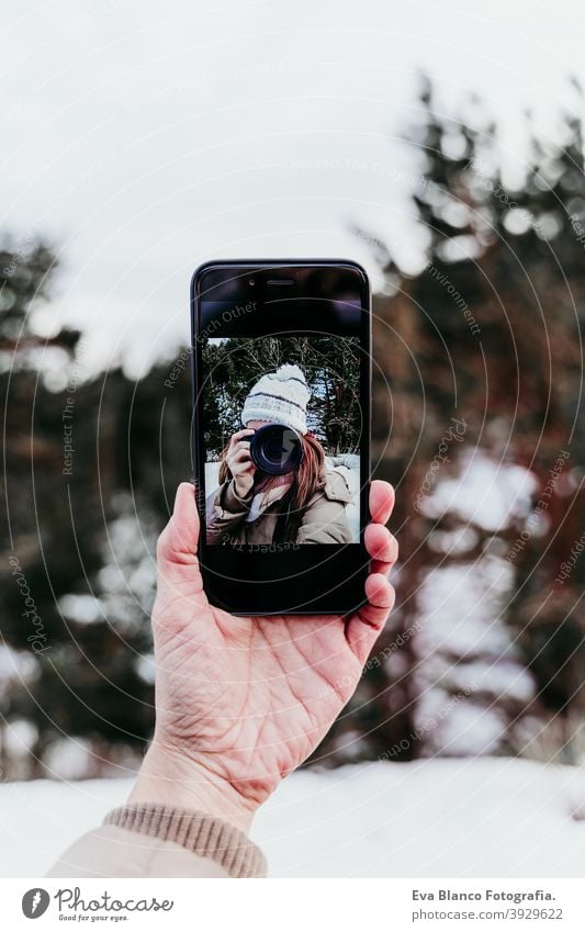 Frau, die ein Bild auf ein Mobiltelefon macht, Selfie. Techonolgie und Lebensstil. Verschneiter Berg Hintergrund Handy Fotokamera Technik & Technologie