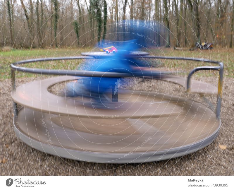 Kind dreht sich auf Drehscheibe auf dem Waldspielplatz und bekommt einen Drehwurm Drehen Feuerwehrauto Spielen Spielplatz Langzeitbelichtung Kindheit Bewegung