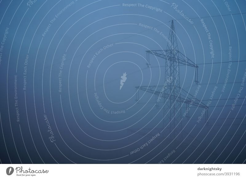 Hochspannungsfreileitung an einem  Mast aus Stahl in Nebel eingehüllt und zur abendlichen blauen Stunde Transportieren Seile Gittermaten Fachwerk statisch