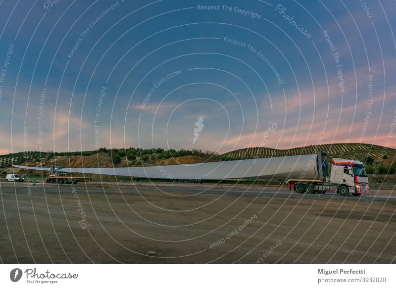 Spezialtransport von Flügeln für Windkraftanlagen, Lkw-Transport eines Windkraftanlagenflügels, der aufgrund seiner Größe einen speziell angepassten Sattelauflieger und Begleitfahrzeuge (oder Galibos) zur Sicherheit benötigt, um andere Verkehrsteilnehmer vor der Gefahr zu warnen.