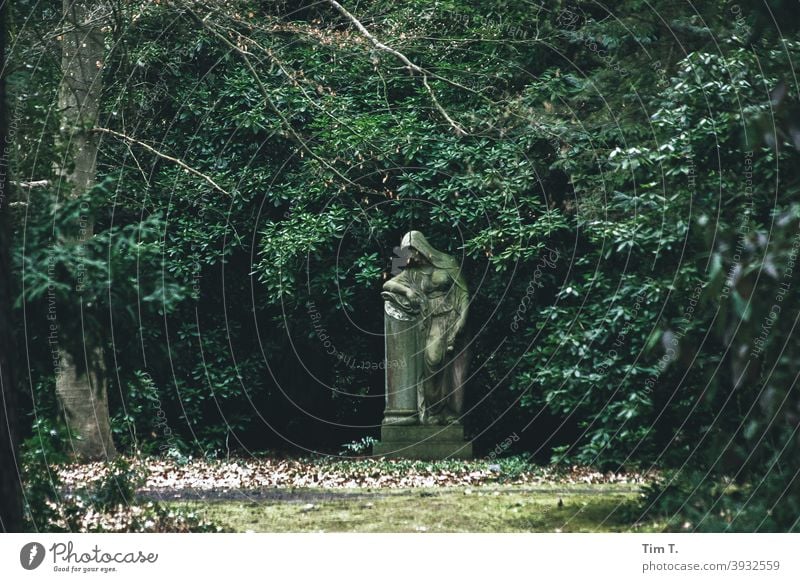 Trauernde Frauenskulptur auf einem Friedhof Skulptur Tod Traurigkeit Außenaufnahme Farbfoto Menschenleer Tag Gedeckte Farben Stein Grabstein alt