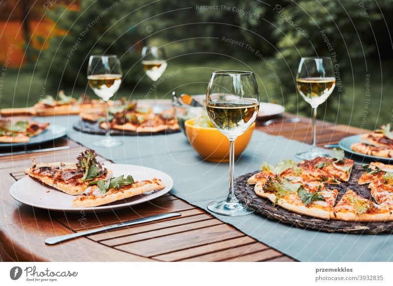 Abendessen in einem Hausgarten. Pizza, Salate, Früchte und Weißwein auf dem Tisch in einem Hinterhof Getränk Feier Speise trinken Essen Festessen Lebensmittel