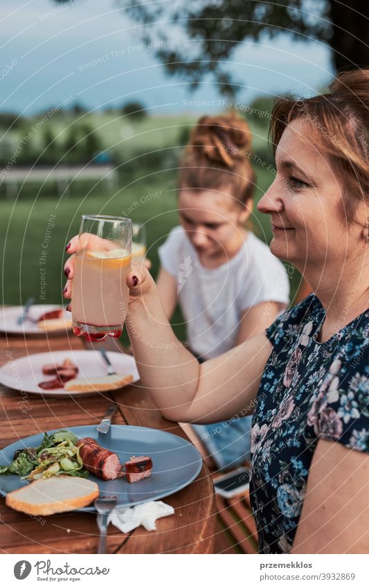 Familie isst während des Sommerpicknicks im Freien in einem Hausgarten zu Abend heimwärts Festessen habend Picknick Lebensmittel Mann Zusammensein Frau Barbecue