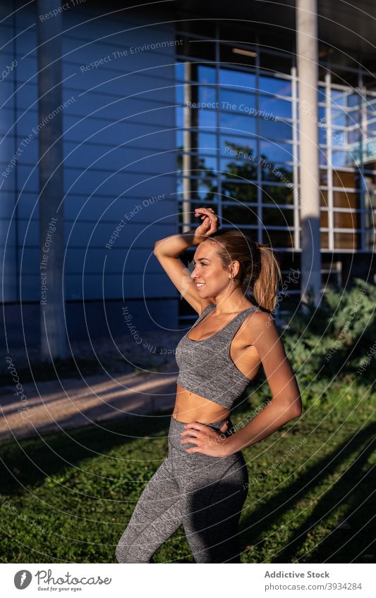 Freudige Sportlerin steht in der Stadt Läufer Großstadt heiter Athlet schlank Sommer passen Frau Sportbekleidung Training jung Lächeln Fitness urban Jogger