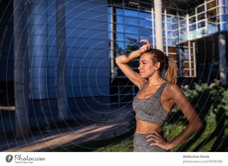 Freudige Sportlerin steht in der Stadt Läufer Großstadt heiter Athlet schlank Sommer passen Frau Sportbekleidung Training jung Lächeln Fitness urban Jogger