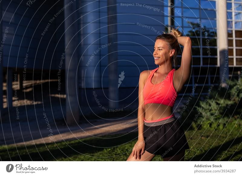 Freudige Sportlerin steht in der Stadt Läufer Großstadt heiter Athlet schlank Sommer passen Frau Sportbekleidung Training jung Lächeln Fitness urban Jogger