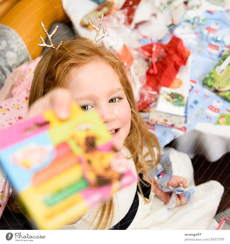 Mädchen mit langen rotblonden Haaren zeigt ihr Weihnachtsgeschenk in die Kamera Weihnachten Bescherung Kind langhaarig Weihnachten & Advent Geschenk Farbfoto