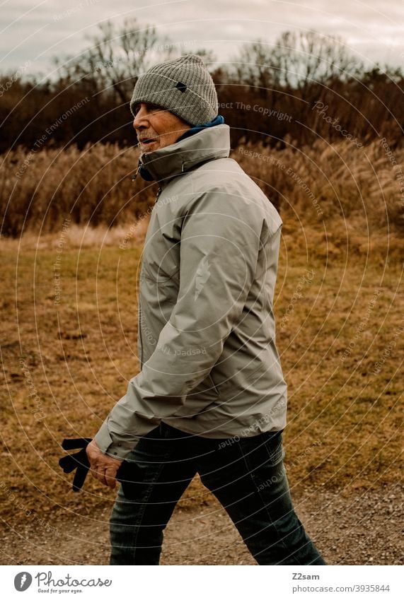 Sportlicher Rentner in der Natur beim spazieren gehen im Freien sportlich rentner Ändern Mann Porträt mütze Winter Kälte Landschaft Wald sträucher freizeit