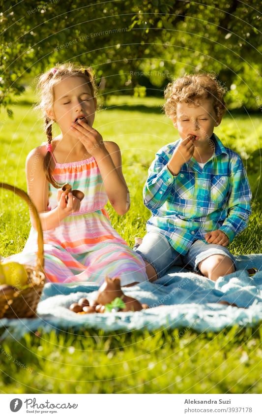 Netter Junge und Mädchen feiern Ostern, suchen und essen Schokoladeneier. Glückliche Familie Urlaub. Glückliche Kinder lachen, lächeln und Spaß haben. Schöner Frühling sonnigen Tag im Park